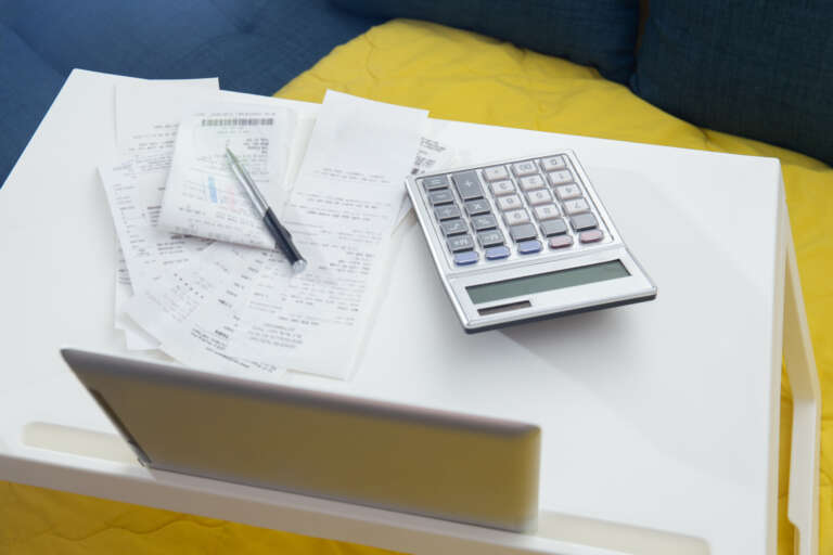 Person reviewing side hustle earnings with a calculator and laptop